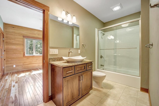 3857 Lake Lucerne Dr, Crandon, WI 54520 - full bathroom featuring vanity, toilet, combined bath / shower with glass door, wood walls, and tile patterned floors