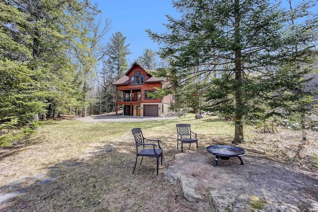 3857 Lake Lucerne Dr, Crandon, WI 54520 - view of grassy yard with a fire pit and an attached garage