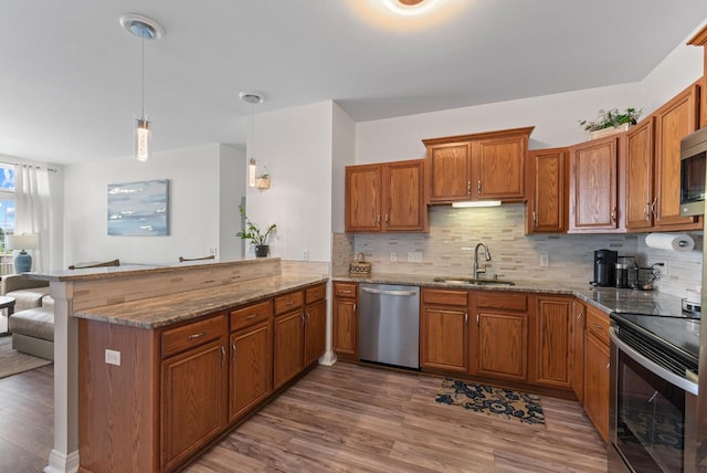 2639 W Honadel Blvd, Oak Creek, WI 53154 - kitchen featuring stainless steel appliances, brown cabinetry, a peninsula, wood finished floors, and stone counters