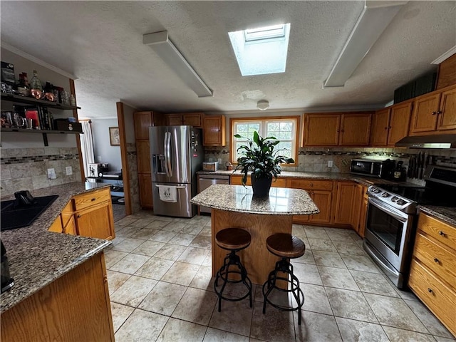 1311 W Northstar Ln, Eau Claire, WI 54703 - kitchen with appliances with stainless steel finishes, under cabinet range hood, backsplash, a skylight, and a textured ceiling