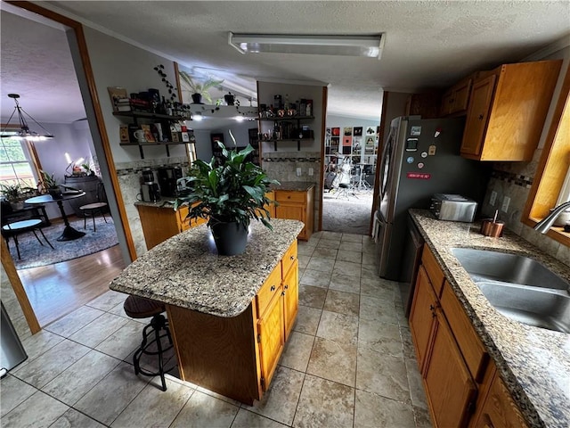 1311 W Northstar Ln, Eau Claire, WI 54703 - kitchen featuring a textured ceiling, brown cabinets, a sink, a breakfast bar, and a center island
