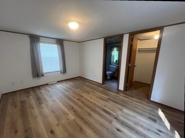 N2639 County Road Z Unit B19, Dousman, WI 53118 - unfurnished bedroom with light wood-style flooring, ensuite bathroom, and a walk in closet