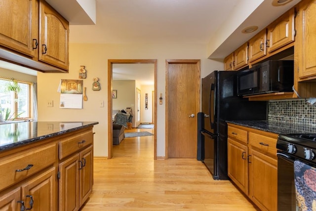 1207 Lark St, Merrill, WI 54452 - kitchen featuring black appliances, light wood-type flooring, brown cabinetry, backsplash, and dark stone counters
