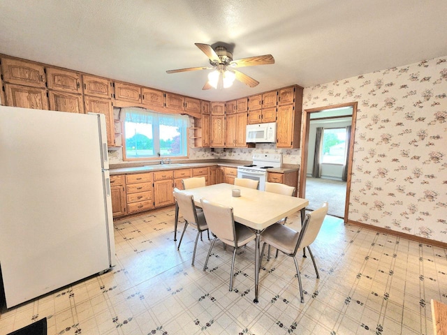 5609 Two Creeks Rd, Two Rivers, WI 54241 - kitchen featuring white appliances, light flooring, a ceiling fan, wallpapered walls, and a sink