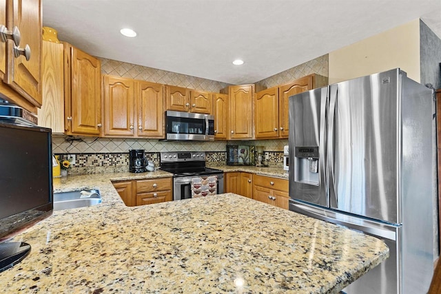 831 Browning Dr, Seymour, WI 54165 - kitchen featuring appliances with stainless steel finishes, light stone countertops, decorative backsplash, brown cabinets, and a peninsula
