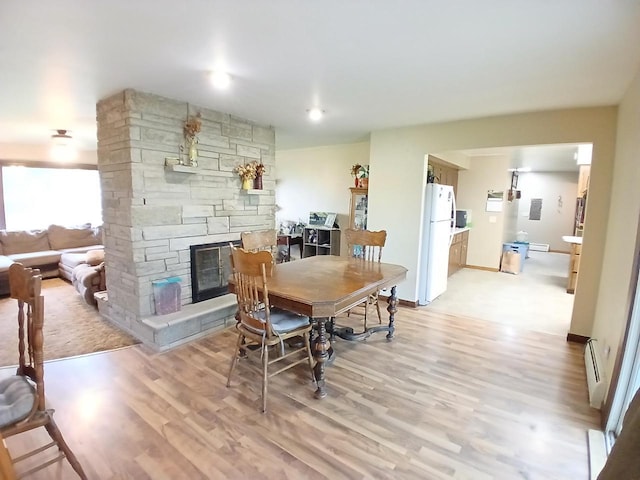 2048 County Road Q, Pound, WI 54161 - dining space with a baseboard heating unit, a stone fireplace, and light wood finished floors