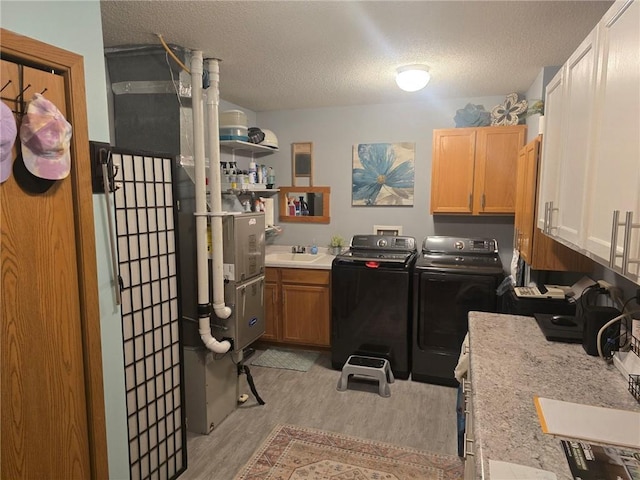 318 Frenette Dr Unit 2, Chippewa Falls, WI 54729 - laundry room featuring washer and dryer, cabinet space, light wood finished floors, and a textured ceiling