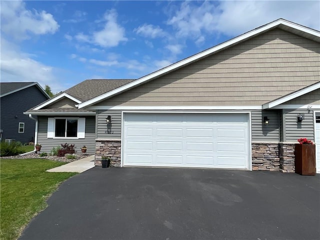 4010 Nicholas Dr, Menomonie, WI 54751 - view of front of house featuring stone siding, an attached garage, and asphalt driveway