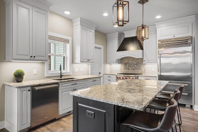 6249 Fountainhead Cir, Deforest, WI 53532 - kitchen with stainless steel appliances, a sink, custom range hood, light wood-style flooring, and tasteful backsplash