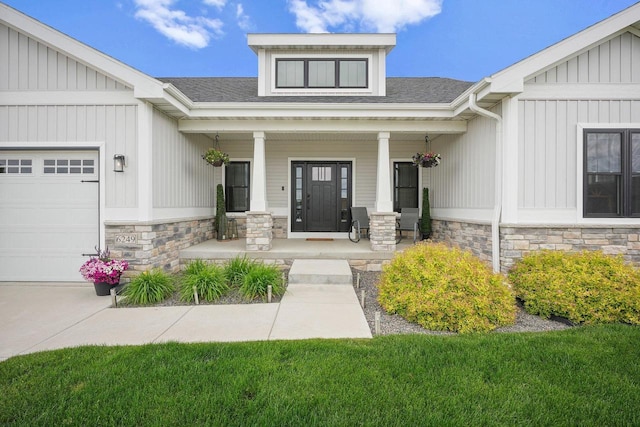 6249 Fountainhead Cir, Deforest, WI 53532 - view of exterior entry with stone siding, a porch, a garage, and roof with shingles