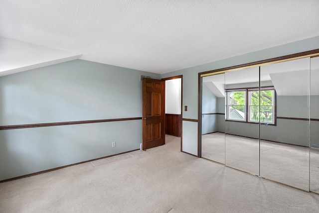 6262 W College Ave, Greendale, WI 53129 - unfurnished bedroom featuring carpet flooring, lofted ceiling, a closet, and a textured ceiling