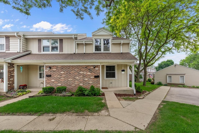 6262 W College Ave, Greendale, WI 53129 - view of front of house with covered porch, board and batten siding, brick siding, and a front lawn