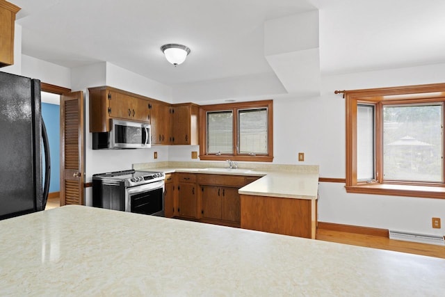 1615 Hickory St, South Milwaukee, WI 53172 - kitchen with stainless steel appliances, light countertops, brown cabinets, wood finished floors, and a baseboard heating unit
