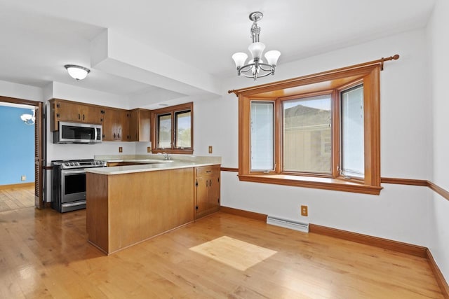 1615 Hickory St, South Milwaukee, WI 53172 - kitchen featuring stainless steel appliances, a peninsula, a chandelier, light wood-style floors, and light countertops