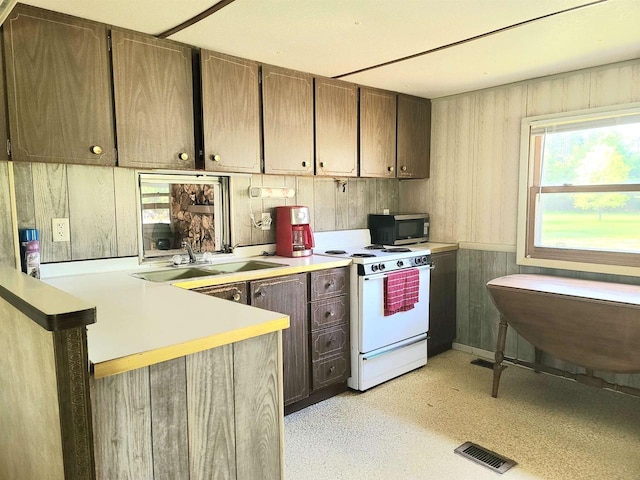 W5677 Alice Ln, New Lisbon, WI 53950 - kitchen featuring white range with electric cooktop, stainless steel microwave, a peninsula, and light countertops