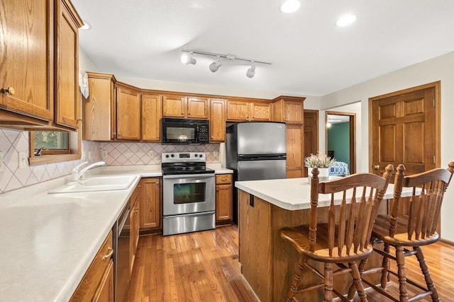 N7844 Lake Shore Ln, Sherwood, WI 54169 - kitchen featuring appliances with stainless steel finishes, brown cabinetry, wood-type flooring, a breakfast bar area, and recessed lighting