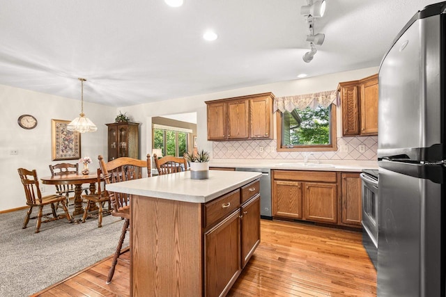 N7844 Lake Shore Ln, Sherwood, WI 54169 - kitchen with stainless steel appliances, a sink, brown cabinetry, decorative backsplash, and light countertops
