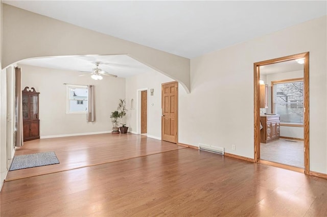 231 S Woodworth St, Elmwood, WI 54740 - unfurnished living room featuring arched walkways, ceiling fan, wood finished floors, and baseboards