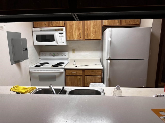 5313 Brody Dr Unit 202, Madison, WI 53705 - kitchen featuring white appliances, brown cabinetry, electric panel, light countertops, and a sink