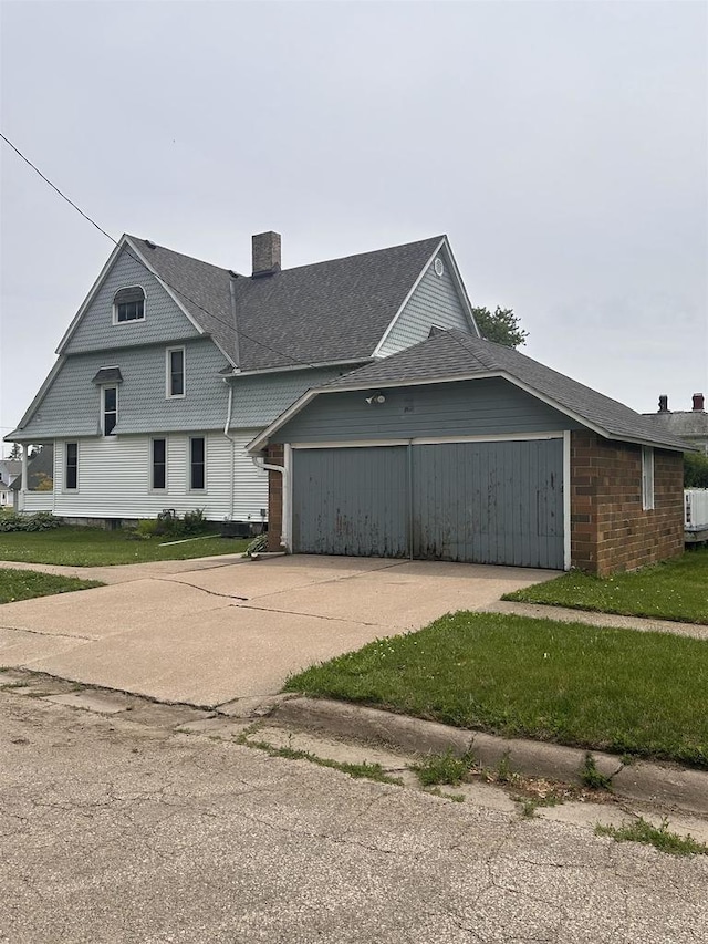 352 N Harrison St, Lancaster, WI 53813 - view of side of property with a garage, concrete driveway, a chimney, and a shingled roof