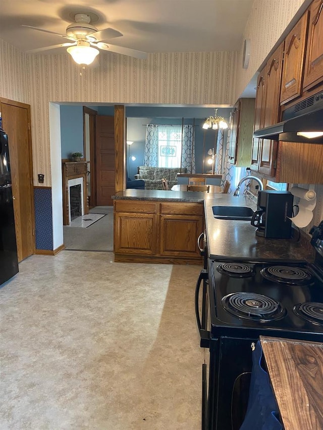 352 N Harrison St, Lancaster, WI 53813 - kitchen with wallpapered walls, black appliances, brown cabinetry, under cabinet range hood, and a ceiling fan