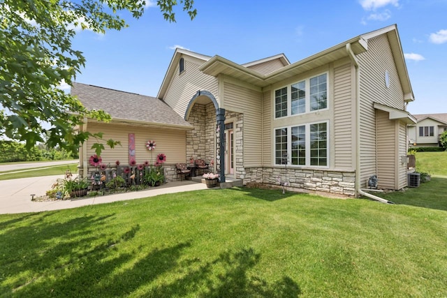 104 Chapel Hill Dr, Johnson Creek, WI 53038 - traditional home with a front yard, stone siding, cooling unit, driveway, and roof with shingles