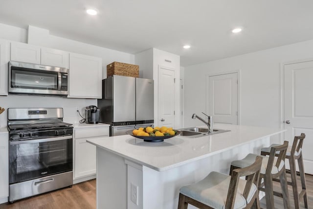 1062 58th Rd, Union Grove, WI 53182 - kitchen featuring stainless steel appliances, a sink, a kitchen bar, wood finished floors, and white cabinets