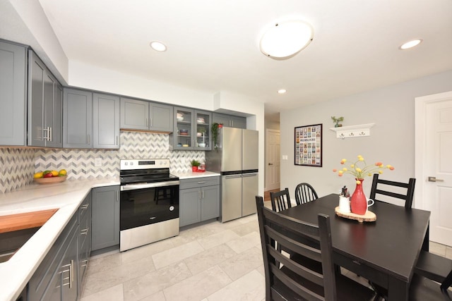 7062 N 46th St, Milwaukee, WI 53223 - kitchen with appliances with stainless steel finishes, tasteful backsplash, gray cabinetry, light countertops, and glass insert cabinets