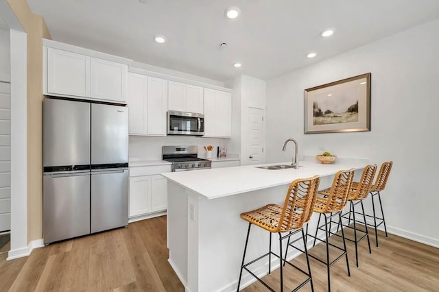1104 58th Rd, Union Grove, WI 53182 - kitchen with stainless steel appliances, a kitchen bar, light wood-type flooring, white cabinets, and recessed lighting