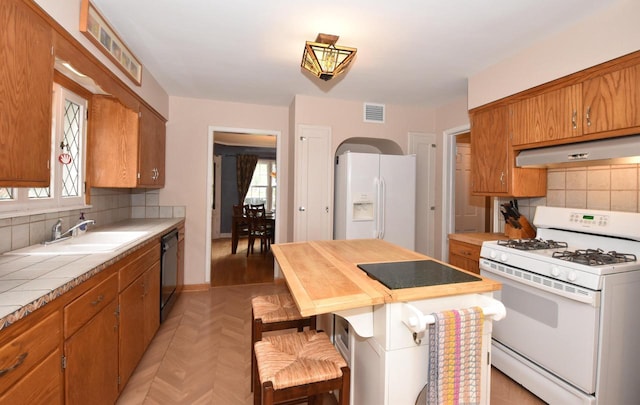3330 S 47th St, Greenfield, WI 53219 - kitchen featuring white appliances, under cabinet range hood, tile countertops, and healthy amount of natural light
