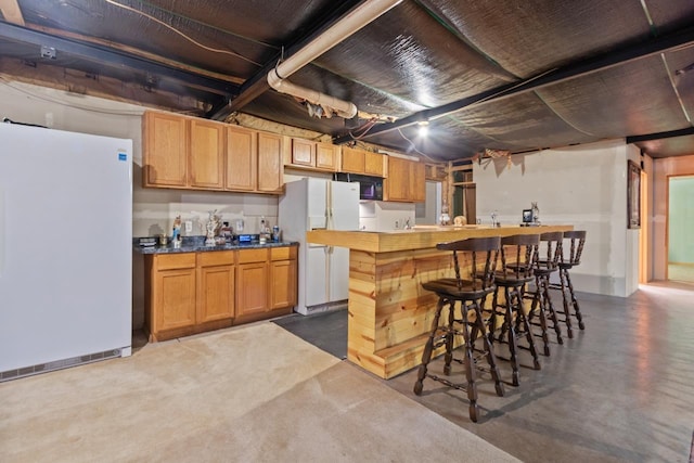227 Cedar St, Ripon, WI 54971 - kitchen featuring freestanding refrigerator, finished concrete floors, a kitchen bar, and black microwave