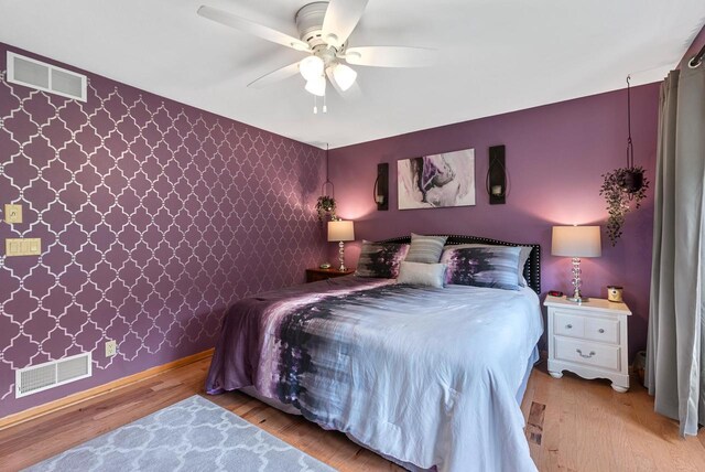 1300 Hidden Fields Dr, West Bend, WI 53095 - bedroom with light wood-type flooring, wallpapered walls, a ceiling fan, and an accent wall