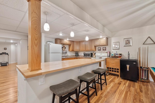 1300 Hidden Fields Dr, West Bend, WI 53095 - kitchen featuring white appliances, wood counters, light wood-type flooring, a kitchen breakfast bar, and a drop ceiling