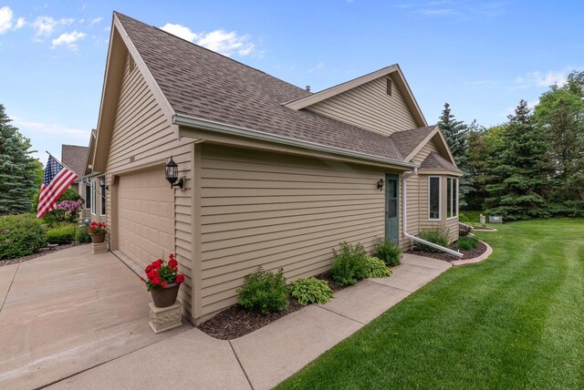 1300 Hidden Fields Dr, West Bend, WI 53095 - view of side of home with roof with shingles, a garage, a yard, and driveway