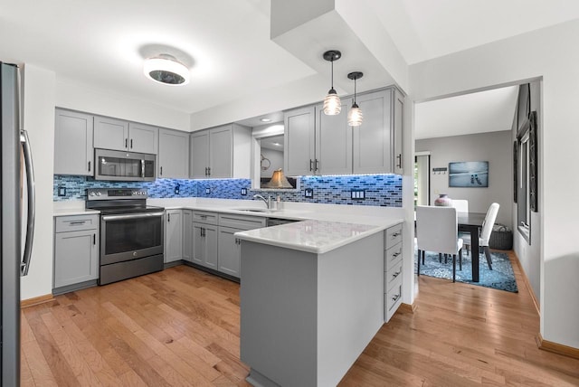 1300 Hidden Fields Dr, West Bend, WI 53095 - kitchen featuring stainless steel appliances, gray cabinets, a peninsula, tasteful backsplash, and light wood-type flooring