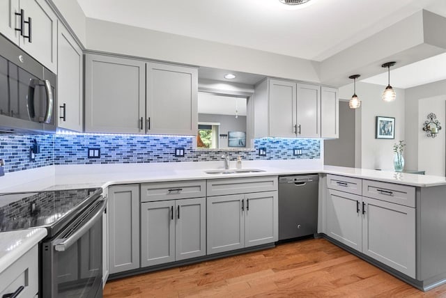 1300 Hidden Fields Dr, West Bend, WI 53095 - kitchen with stainless steel appliances, gray cabinetry, a peninsula, light wood finished floors, and light countertops