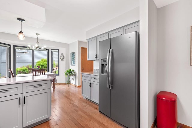 1300 Hidden Fields Dr, West Bend, WI 53095 - kitchen with stainless steel refrigerator with ice dispenser, gray cabinetry, light countertops, light wood-style flooring, and a chandelier