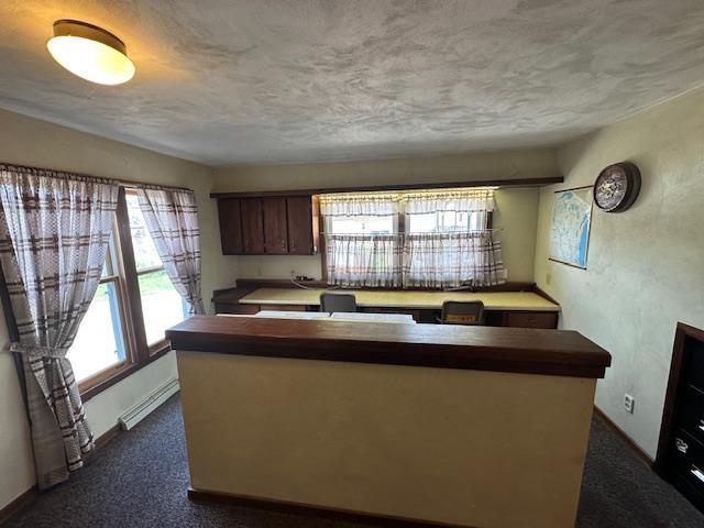 420 Jackson St, Waupun, WI 53963 - kitchen featuring dark colored carpet, a center island, baseboards, and a textured ceiling