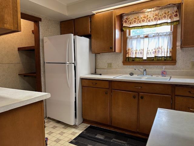 420 Jackson St, Waupun, WI 53963 - kitchen featuring freestanding refrigerator, a sink, light countertops, light floors, and brown cabinets