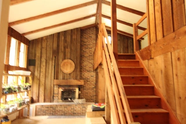 4726 N Green Bay Rd, Racine, WI 53404 - staircase featuring wooden walls, vaulted ceiling, and a brick fireplace