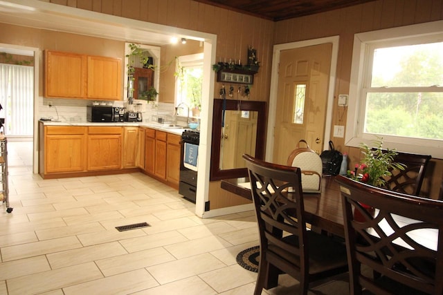 4726 N Green Bay Rd, Racine, WI 53404 - kitchen with black range with gas cooktop, light countertops, a sink, plenty of natural light, and wooden walls