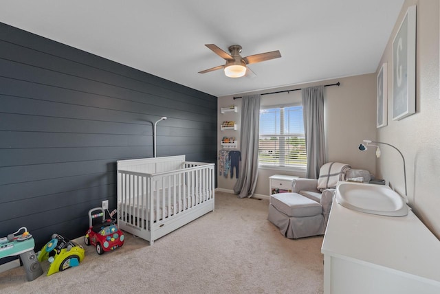 6028 Star Grass Ln, Racine, WI 53406 - bedroom with a nursery area, light carpet, ceiling fan, and wood walls