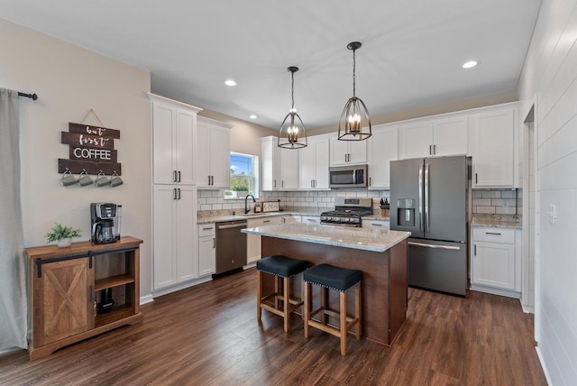 6028 Star Grass Ln, Racine, WI 53406 - kitchen featuring appliances with stainless steel finishes, white cabinets, dark wood-style floors, a center island, and decorative backsplash