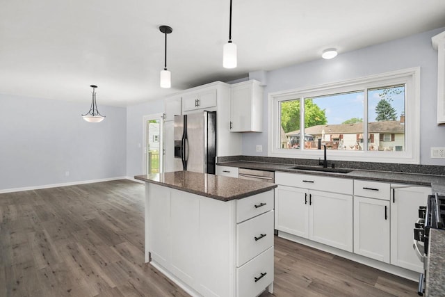 2711 Hyacinth Ave, Janesville, WI 53545 - kitchen with appliances with stainless steel finishes, wood finished floors, a center island, white cabinets, and hanging light fixtures