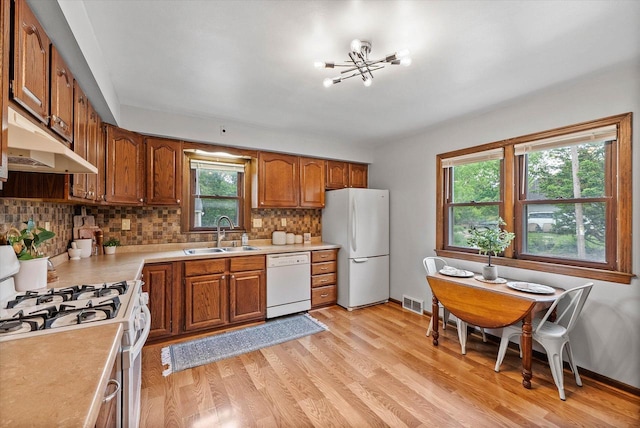 7838 N Sherman Blvd, Brown Deer, WI 53209 - kitchen featuring white appliances, under cabinet range hood, light countertops, brown cabinetry, and a chandelier