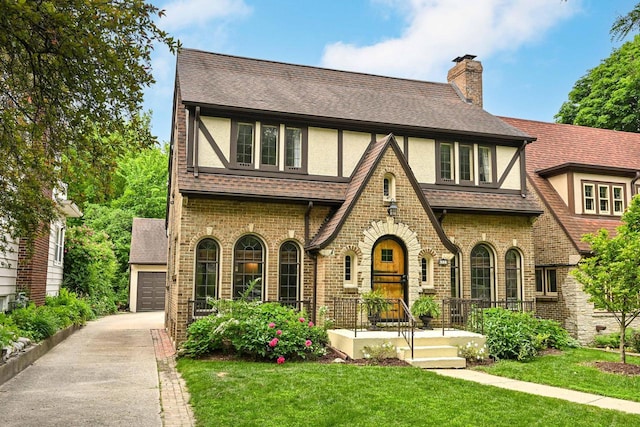 6223 W Wisconsin Ave, Wauwatosa, WI 53213 - tudor-style house featuring a front yard, brick siding, a chimney, and a shingled roof