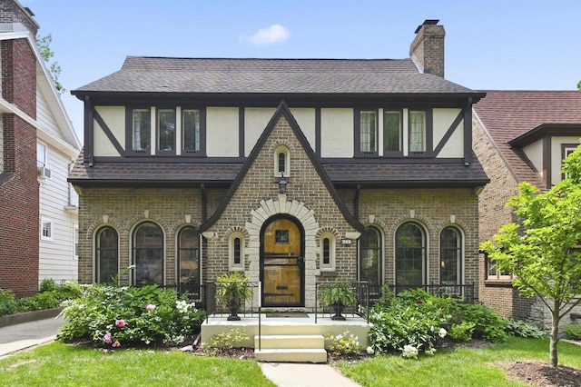 6223 W Wisconsin Ave, Wauwatosa, WI 53213 - english style home with stucco siding, covered porch, roof with shingles, brick siding, and a chimney