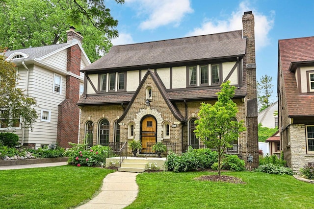 6223 W Wisconsin Ave, Wauwatosa, WI 53213 - english style home with a front lawn, a shingled roof, and brick siding