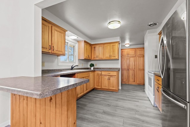 N1128 County Rd W, Fremont, WI 54940 - kitchen with freestanding refrigerator, a peninsula, white electric range oven, dark countertops, and light wood finished floors