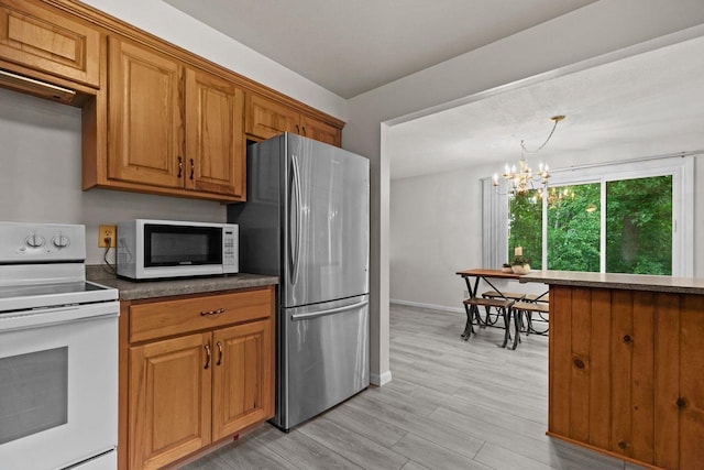 N1128 County Rd W, Fremont, WI 54940 - kitchen featuring white appliances, brown cabinetry, dark countertops, a chandelier, and light wood-style floors